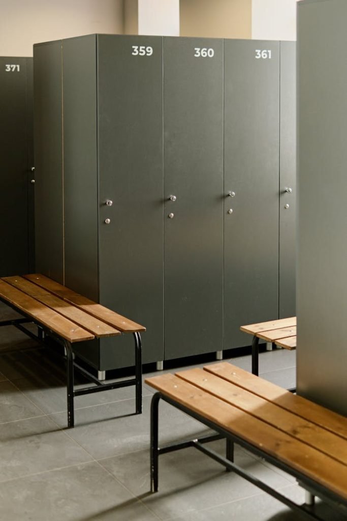 Spacious locker room featuring grey lockers and wooden benches, ideal for fitness centers.